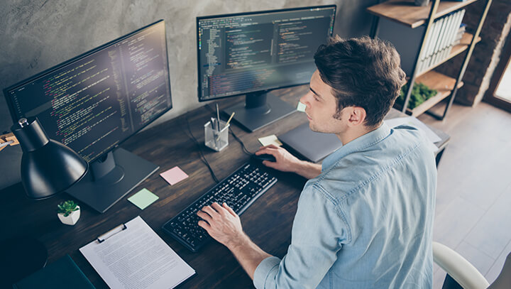 male worker at desk working on laptop for IT services